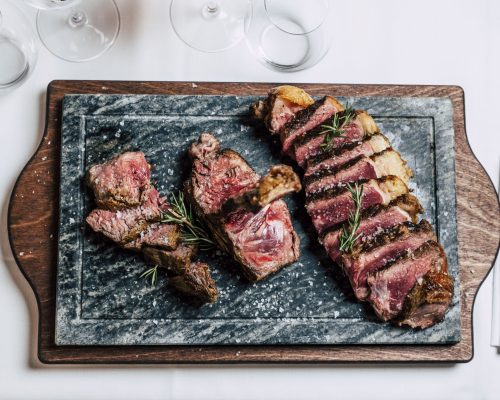 Fiorentina di scottona alla griglia con patate sabbiose dorate, servita su tagliere caldo in pietra alla Locanda da Ruggero.